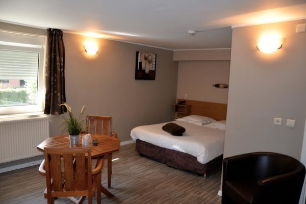 81863520 Chambre double de l’Hôtel le Midi avec table ronde et fauteuil